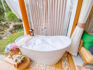 a white bath tub sitting in front of a window at Pangthara65 ปางธารา ณ ปางไฮ เชียงใหม่ in Doi Saket