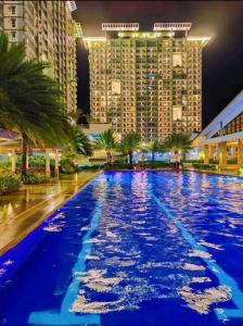 a large pool with blue water in front of tall buildings at Verdon Parc 2Br Comfy Resort facing Samal island! in Davao City