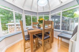 a dining room with a table and chairs and windows at Wayside Bungalow in Staveley