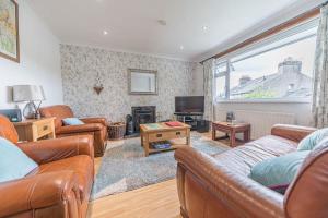 a living room with leather couches and a television at Wayside Bungalow in Staveley