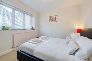 1 dormitorio con 1 cama con sábanas blancas y ventana en Stylish Retreat - 2Bed Home with Exposed Beams - Apex Stays, en Stamford