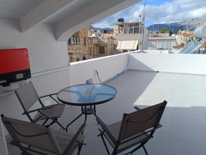 y balcón con mesa de cristal y sillas. en DATA Maisonettes and more, en Chios