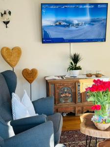 a living room with two chairs and a tv on the wall at Appartement Alpenhof Wildschönau in Niederau