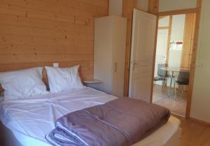 uma cama num quarto com uma parede de madeira em Camping Les Peupliers du Lac Onlycamp em Chindrieux