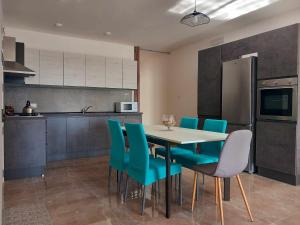 a kitchen with a dining table and blue chairs at Apartment in Marsaskala in Marsaskala