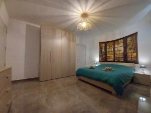 a bedroom with a green bed and a chandelier at Apartment in Marsaskala in Marsaskala