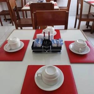a table with red napkins and white plates on it at Hotel Chantilly in Presidente Prudente