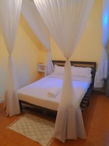 1 dormitorio con 1 cama con cortinas blancas en Elite stays kisumu en Kisumu