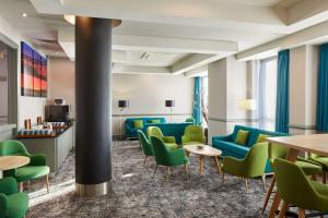 a waiting room with green chairs and tables at Leonardo Hotel Newcastle in Newcastle upon Tyne