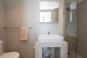 La salle de bains blanche est pourvue d'un lavabo et de toilettes. dans l'établissement 15 Bronze Bay Umhlanga Rocks, à Durban