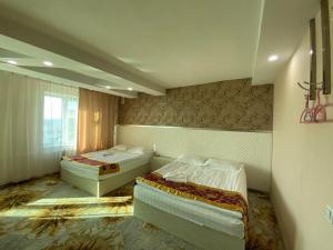 een hotelkamer met 2 bedden en een raam bij Jasper Hotel in Darhan