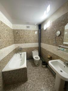 a bathroom with a tub and a toilet and a sink at Jasper Hotel in Darhan