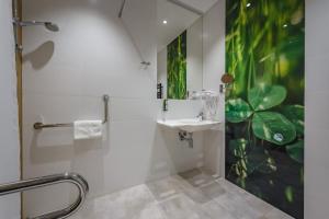 La salle de bains est pourvue d'un lavabo et d'une douche. dans l'établissement Hotel Prezydent, à Spała