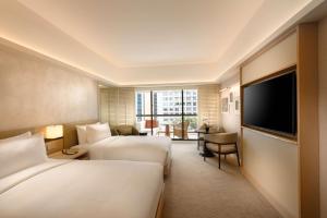 ein Hotelzimmer mit 2 Betten und einem Flachbild-TV in der Unterkunft Conrad Singapore Orchard in Singapur