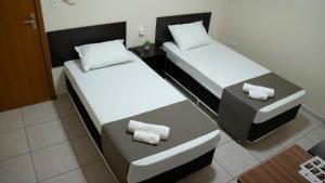 um pequeno quarto com duas camas e um banco em Dom Hotel Maringá em Maringá