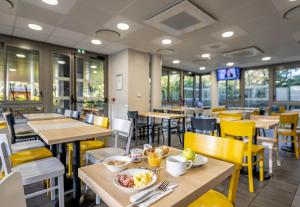 a dining room with tables and yellow chairs at B&B HOTEL Bordeaux Langon in Langon