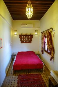 a bedroom with a red bed and a chandelier at Dar Saray in F&egrave;s