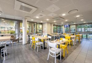 a dining room with tables and yellow chairs at B&B HOTEL Bordeaux Langon in Langon