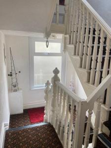 a white staircase in a room with a window at Villa Guest House in Porthcawl