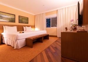 a hotel room with a large bed and a window at Grande Hotel Campos do Jordao in Campos do Jordão