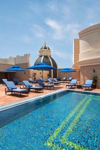 a pool with chairs and umbrellas next to a building at Royal Rose Abu Dhabi in Abu Dhabi