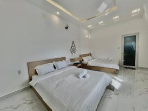 two beds in a room with white walls at CT Villa in Xuan An
