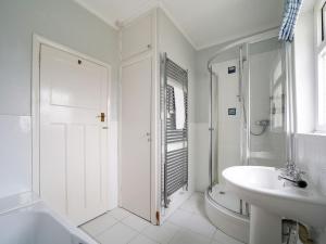 a white bathroom with a shower and a sink at Trevarthian in Polzeath +28 photos