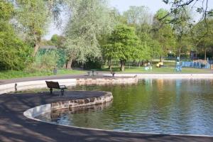 a park with a bench in front of a pond at Lovely 3 Bed House in Runcorn in Runcorn