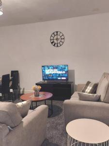 een woonkamer met banken en een tv en een klok bij 4-Bed House in Accrington in Accrington