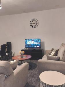 a living room with couches and a tv and a clock at 4-Bed House in Accrington in Accrington