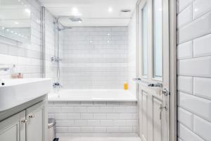 a white bathroom with a tub and a sink at Victoria Belgravia Townhouse Apartments in London