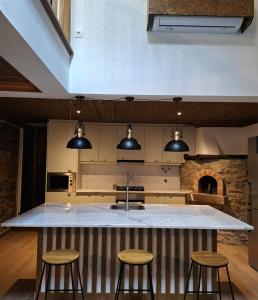 a kitchen with a large island with three bar stools at Porta 28 in Penacova