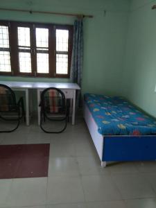Zimmer mit einem Bett, einem Tisch und 2 Stühlen in der Unterkunft Nature stay-the Himalayan foot hills -JANAKI SADAN in Jhājra