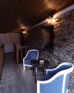 Habitación con 2 sillas, mesa y pared de piedra. en Porta 28 en Penacova