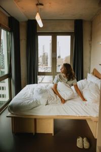 Hotel Jansen Amsterdam Bajeskwartier في أمستردام: امرأة تجلس على سرير أمام النافذة