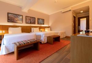 a hotel room with two beds and a red rug at Grande Hotel Campos do Jordao in Campos do Jordão