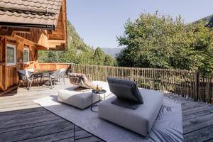 a wooden deck with a couch and a laptop on it at Moxn Chalet Lungau - Authentic Luxury Living in Ramingstein