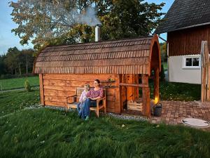 a woman and a child sitting in front of a play house at Ferienhof Greuthof in Bad Wurzach