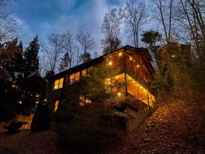 uma casa iluminada à noite com luzes acesas em Spacious Resort Log Cabin, Easy Drive, Hot Tub, Arcade Gameroom, Mountain Vibe em Gatlinburg