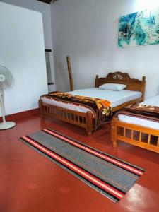 two twin beds in a room with a rug at A Madan Homestay in Napoklu