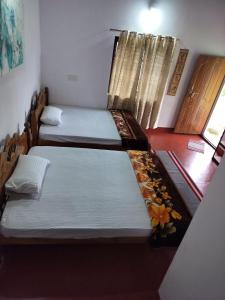 twee bedden in een kamer met een raam bij A Madan Homestay in Napoklu