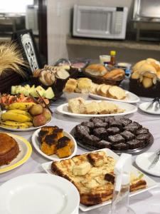 een tafel vol met verschillende soorten levensmiddelen op borden bij Hotel Pousada em frente ao Nações Shopping in Criciúma