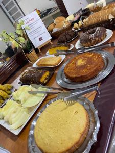 een tafel met taarten en ander voedsel op borden bij Hotel Pousada em frente ao Nações Shopping in Criciúma