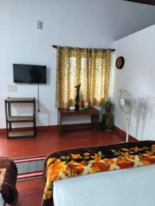 a living room with a bed and a tv and a room at A Madan Homestay in Napoklu