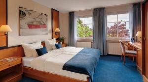 ニュルブルクにあるモータースポーツ ホテルのベッド、デスク、窓が備わるホテルルームです。