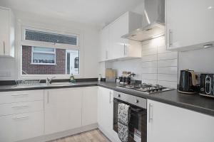 uma cozinha branca com um lavatório e um fogão em Sleek & Tranquil Corner on Durham Road, Sleeps 4 em Lackenby