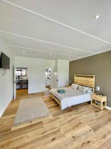 Schlafzimmer mit einem Bett und Holzboden in der Unterkunft Brummer House - Living The Breede in Malgas