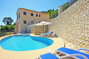 a swimming pool with chairs and an umbrella and a house at Villa Lia - PlusHolidays in Calpe
