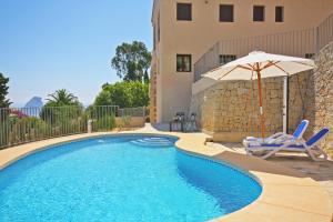 a swimming pool with an umbrella and two chairs and an umbrella at Villa Lia - PlusHolidays in Calpe