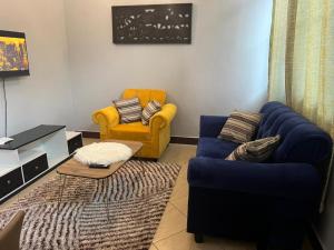 salon z niebieską kanapą i żółtym krzesłem w obiekcie Stunning, Romantic and Luxurious Apartment w mieście Dar es Salaam
